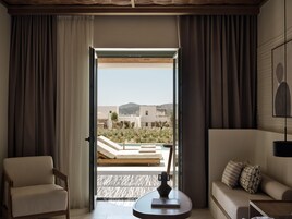 Una habitación con vista a una piscina y edificios, un sofá, una silla y una mesa con un jarrón.