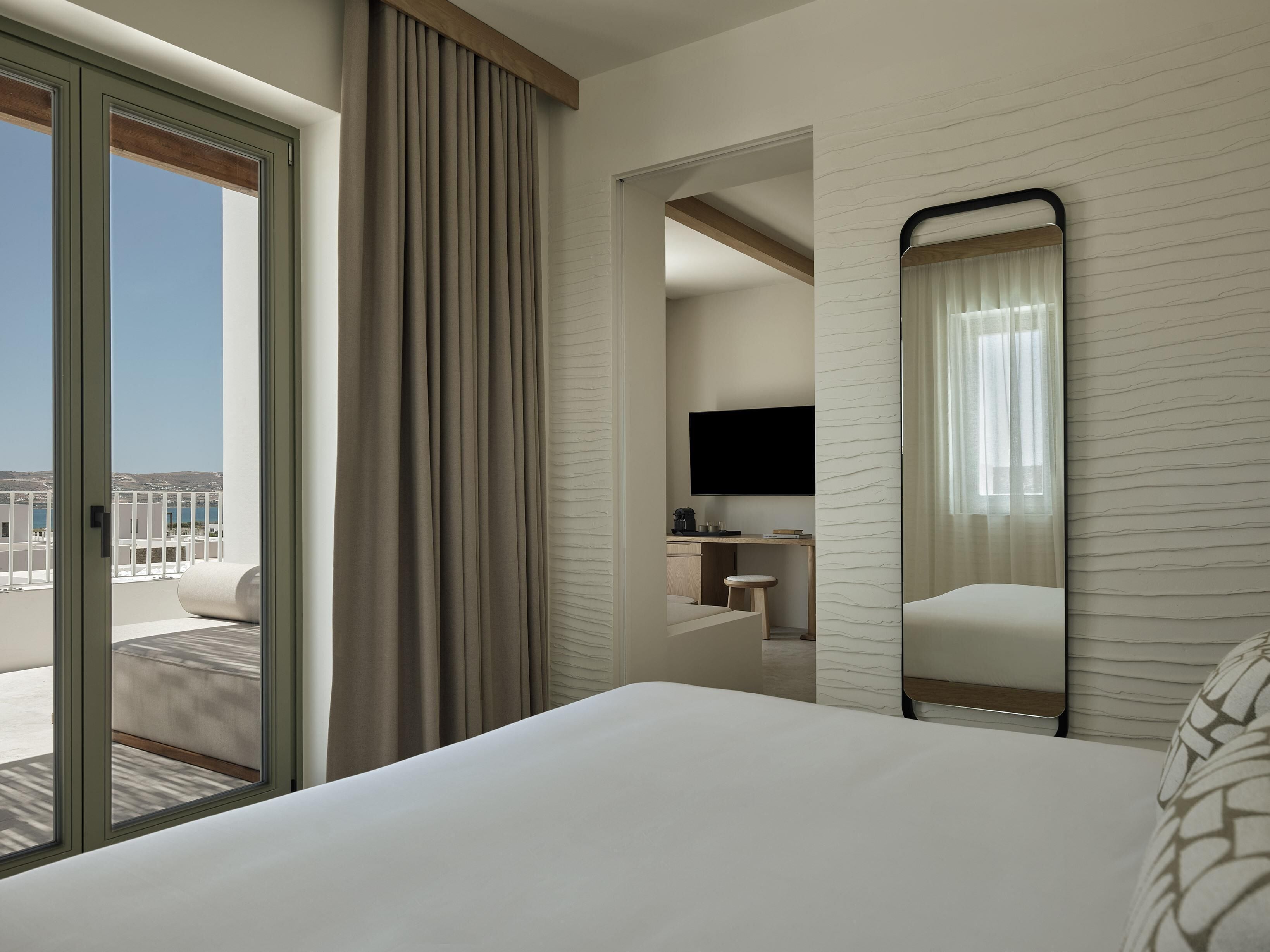 Une chambre d’hôtel avec un lit, un bureau avec une télévision, une chaise et une vue sur l’extérieur.