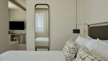 A hotel room with a bed, a desk, a television, and a mirror.