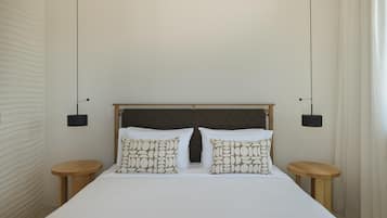 Une chambre d’hôtel avec un grand lit, deux tables de chevet et une tête de lit ornée d’un motif quadrillé.