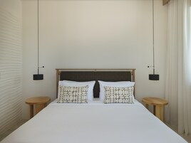 Una habitación de hotel con una cama grande, dos mesitas de noche y un cabecero con diseño de cuadrícula.