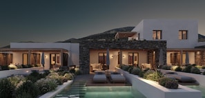 A modern house with a swimming pool, stone walls, and outdoor seating.