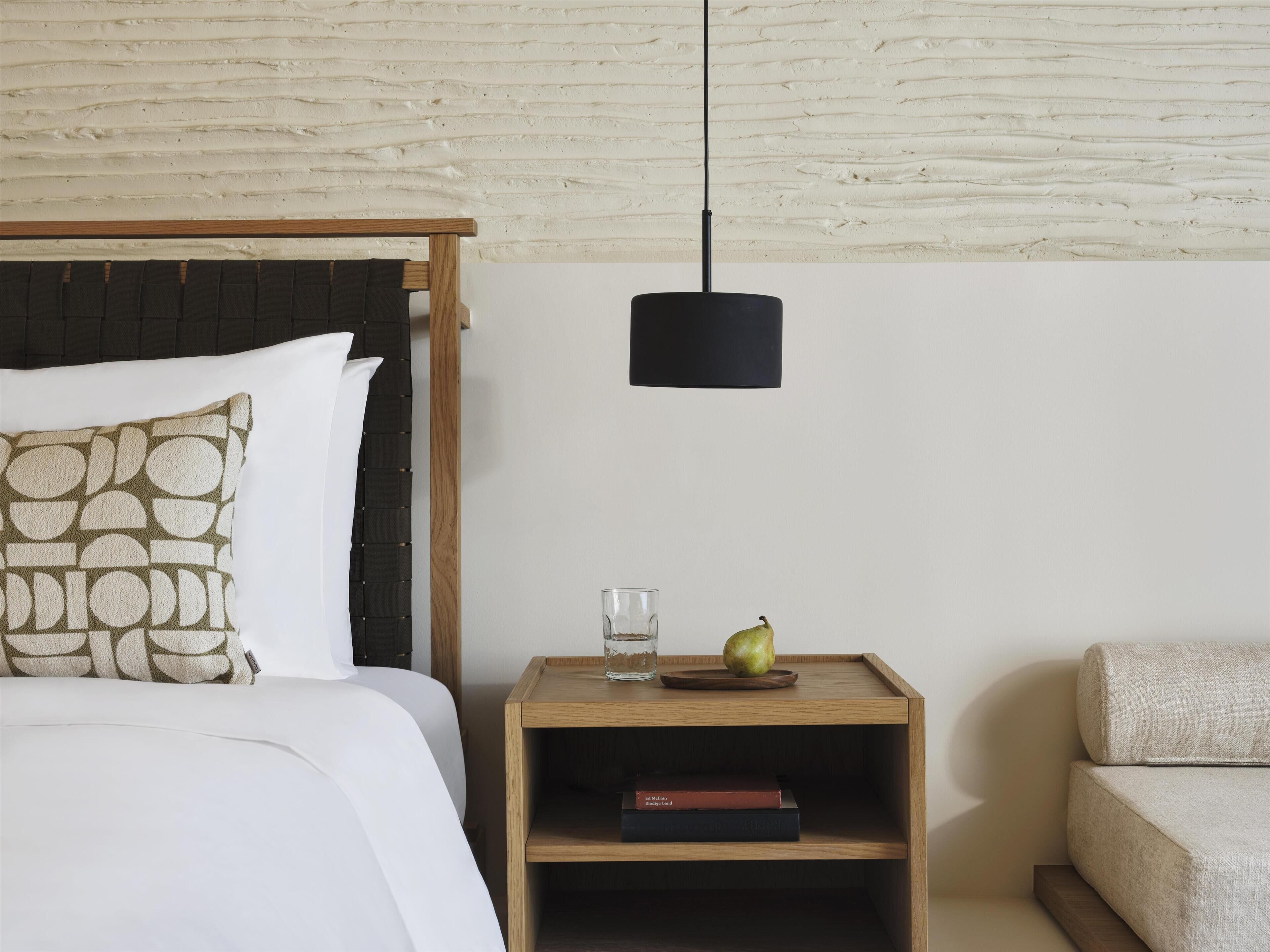 A neatly arranged bedroom with a bed, bedside table, and a small nightstand.