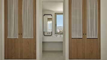 A hallway with wooden doors and a view into a bathroom with a mirror and sink.
