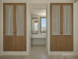 Un pasillo con puertas de madera y vista hacia un baño con espejo y lavamanos.