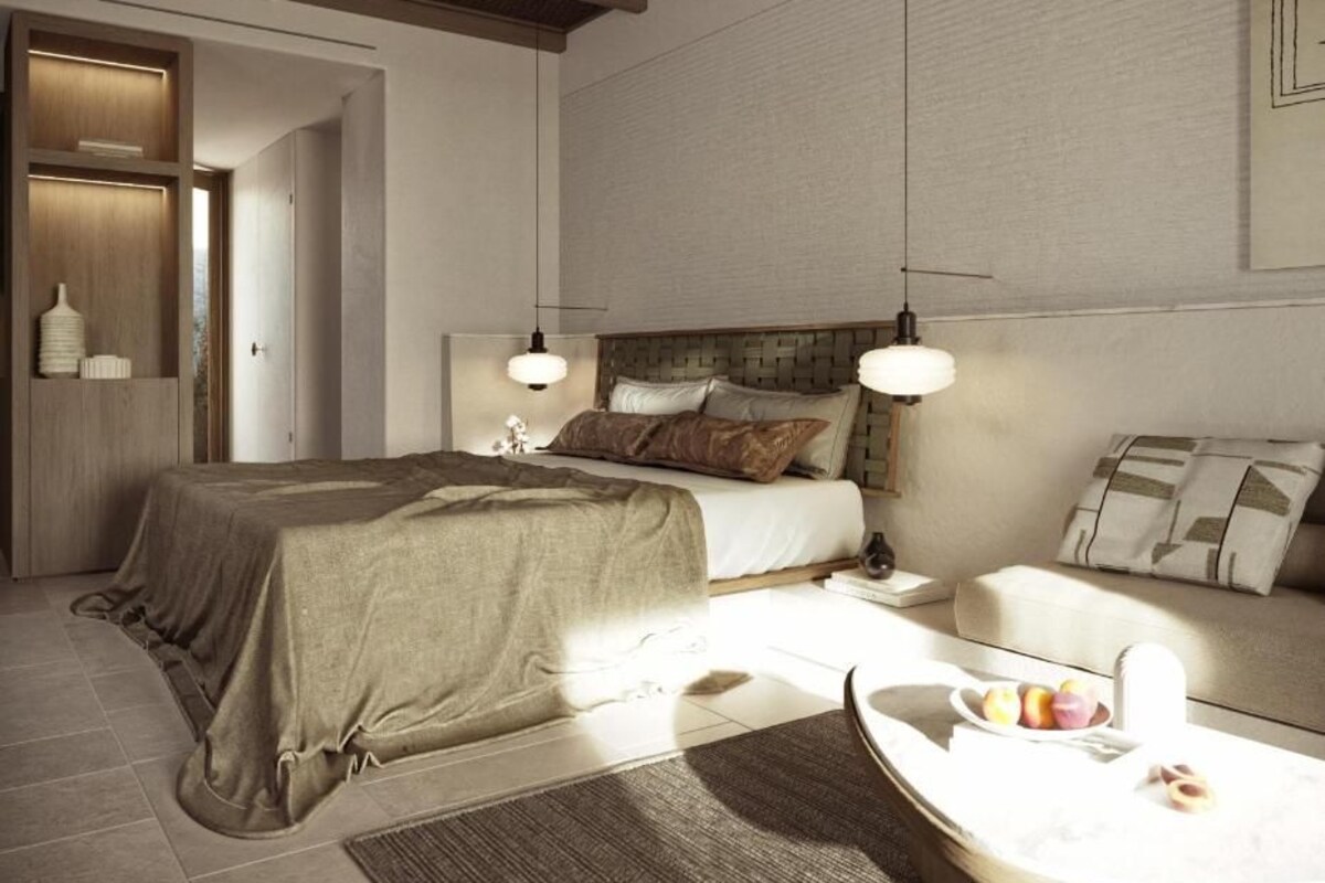Un dormitorio moderno con una cama grande, mesitas de noche, un sofá y una mesa de comedor con fruta.