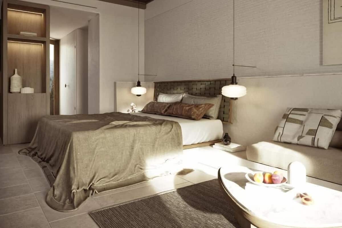 Une chambre moderne avec un grand lit, des tables de chevet, un canapé et une table à manger agrémentée de fruits.