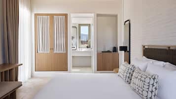 A bedroom with a large bed, wooden wardrobe, and a bathroom with a mirror and sink.