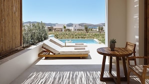 Ein moderner Außenbereich mit Pool, Holzmöbeln und Blick auf eine Küstenlandschaft.