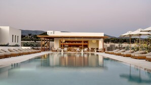 A modern outdoor pool area with lounge chairs and a bar. - Parian Chronicle Hotel Paros, Destination by Hyatt (Paros)