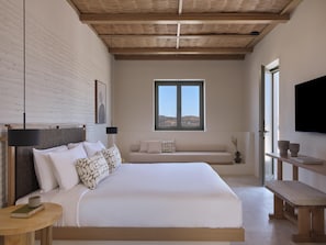 A bedroom with a large bed, a window, a flat-screen TV, and a wooden bench. - Parian Chronicle Hotel Paros, Destination by Hyatt (Paros)