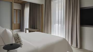 Une chambre d’hôtel moderne équipée d’un grand lit, d’un bureau, d’une télévision et d’une armoire.