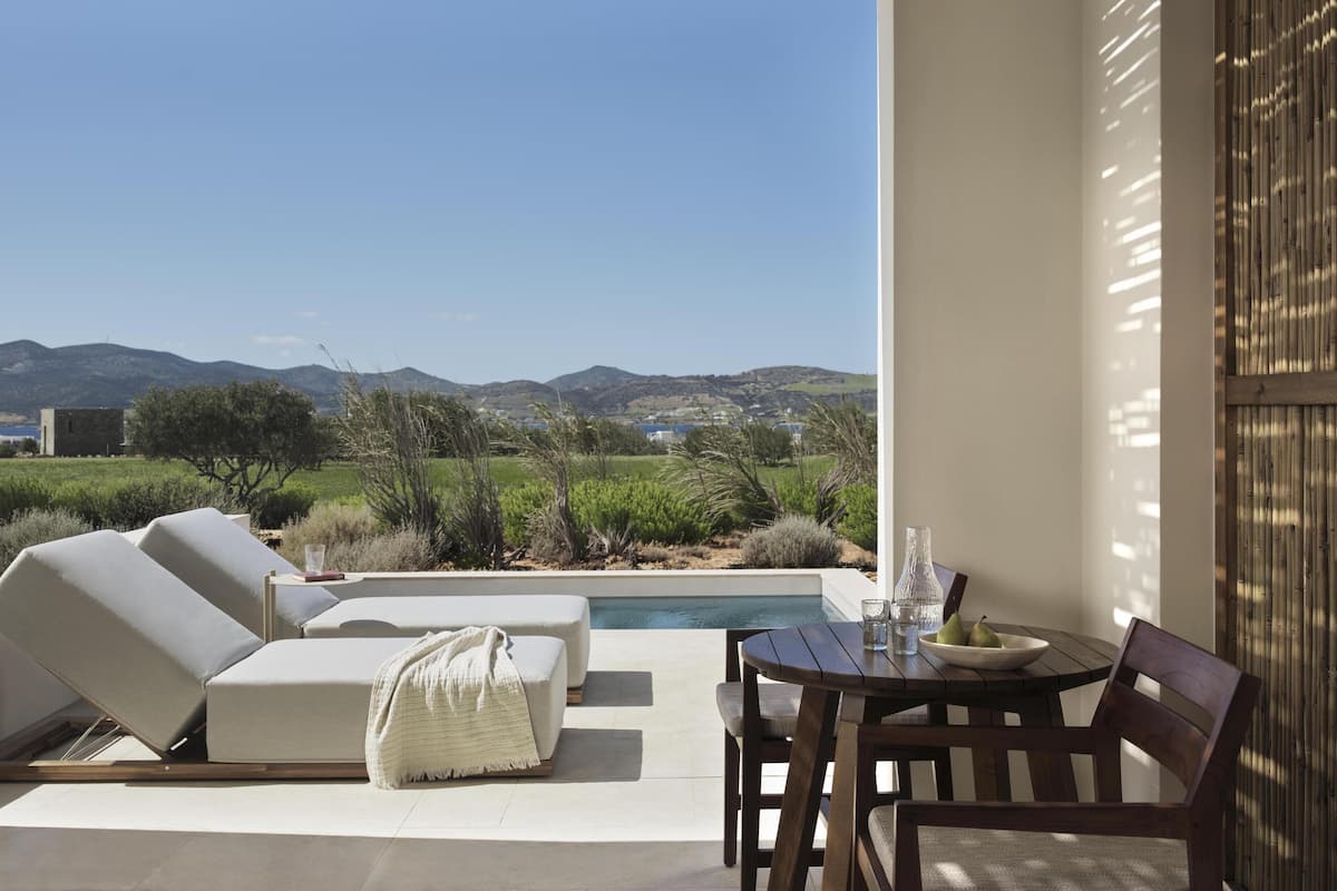 Une terrasse avec une piscine, des chaises longues et une table avec des chaises.