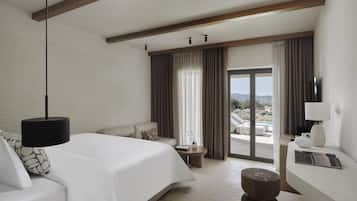 Une chambre d’hôtel avec un lit, un canapé, une petite table, une télévision et une vue sur une piscine et un paysage.