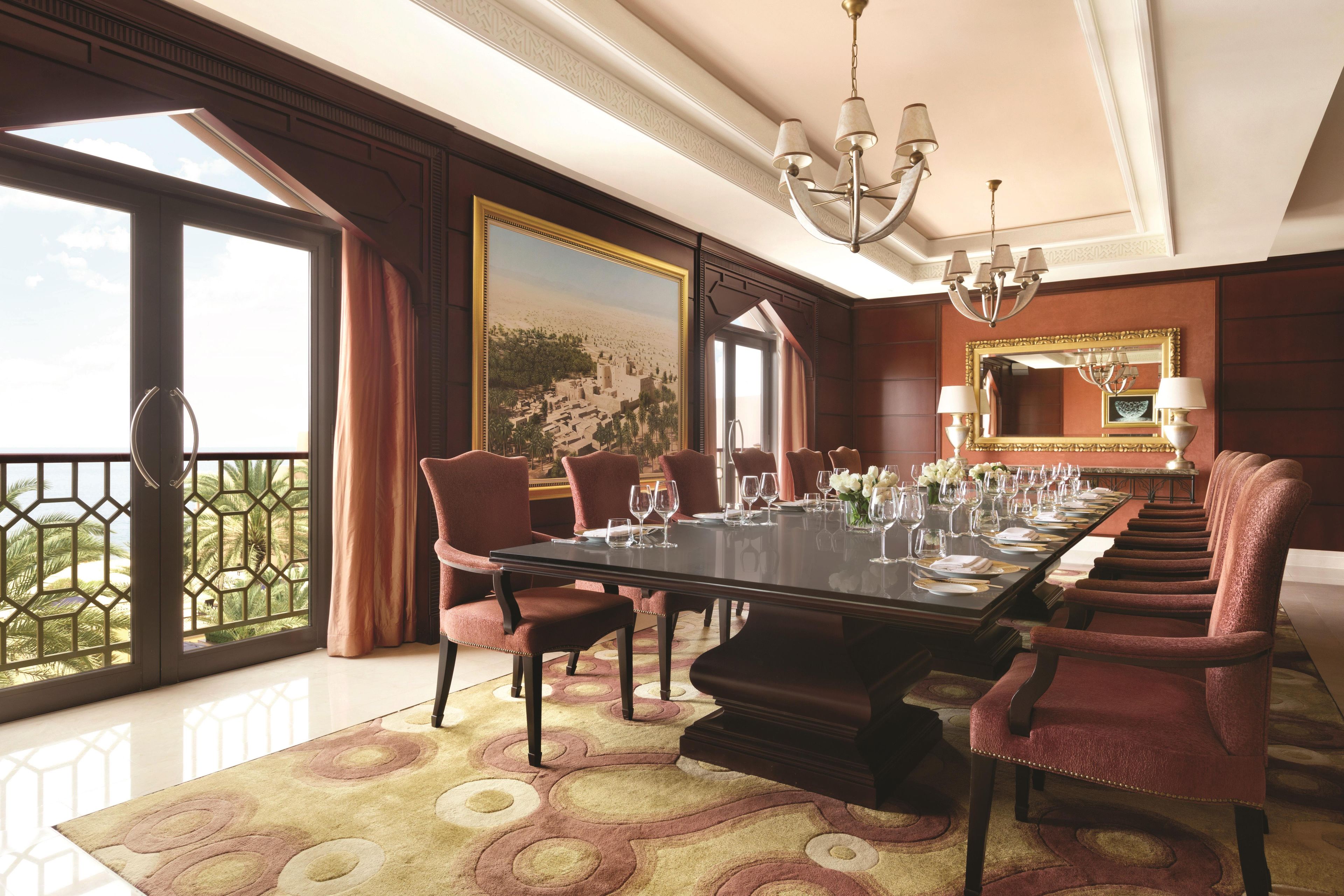 A formal dining room with a long table, chairs, and a chandelier.
