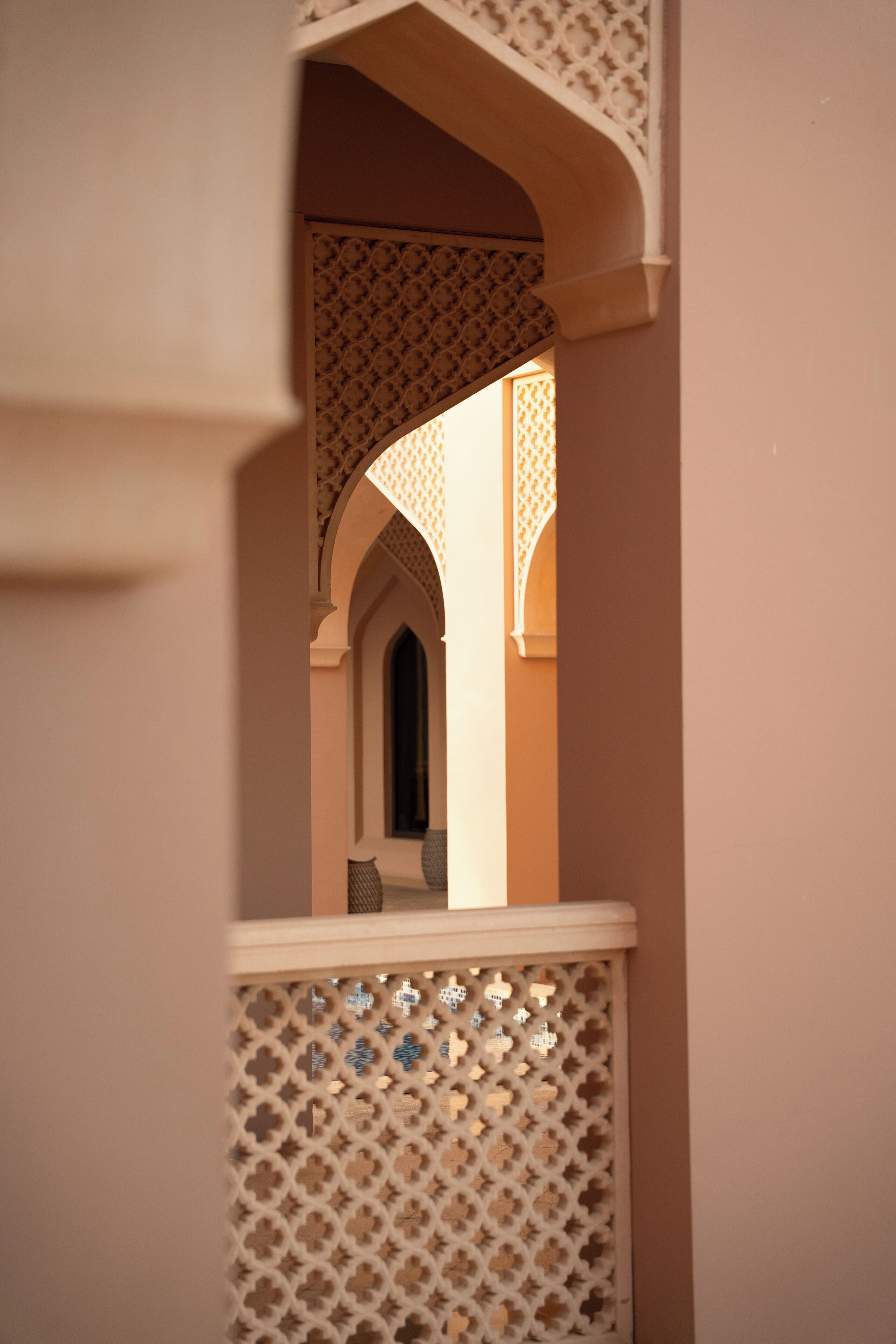 An interior view of a corridor with ornate arches and lattice work.