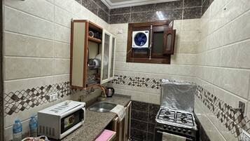 Una cocina compacta equipada con microondas, tostadora, pileta y cocina a gas.