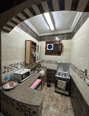 Una cocina compacta equipada con microondas, tostadora, pileta y cocina a gas.