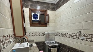 A kitchen with a granite countertop, a gas stove, a microwave, and a sink. - Luxe Nest (Luxor)
