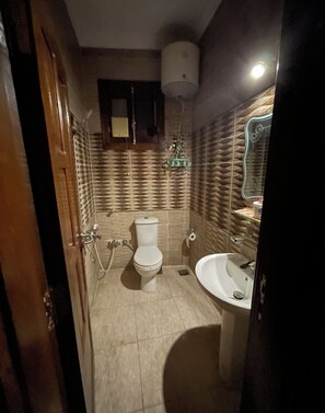 A bathroom with a toilet, sink, and a mirror. - Luxe Nest (Luxor)