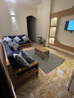 Una sala de estar con un sofá, una mesa de centro y un televisor montado en la pared.