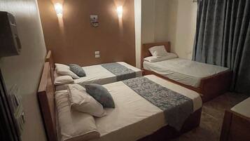 Una habitación de hotel con dos camas individuales, un ventilador de techo y lámparas de noche.