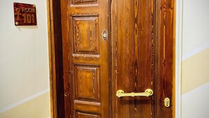 A wooden door with a brass handle and a room number sign on the wall. - Luxe Nest (Luxor)