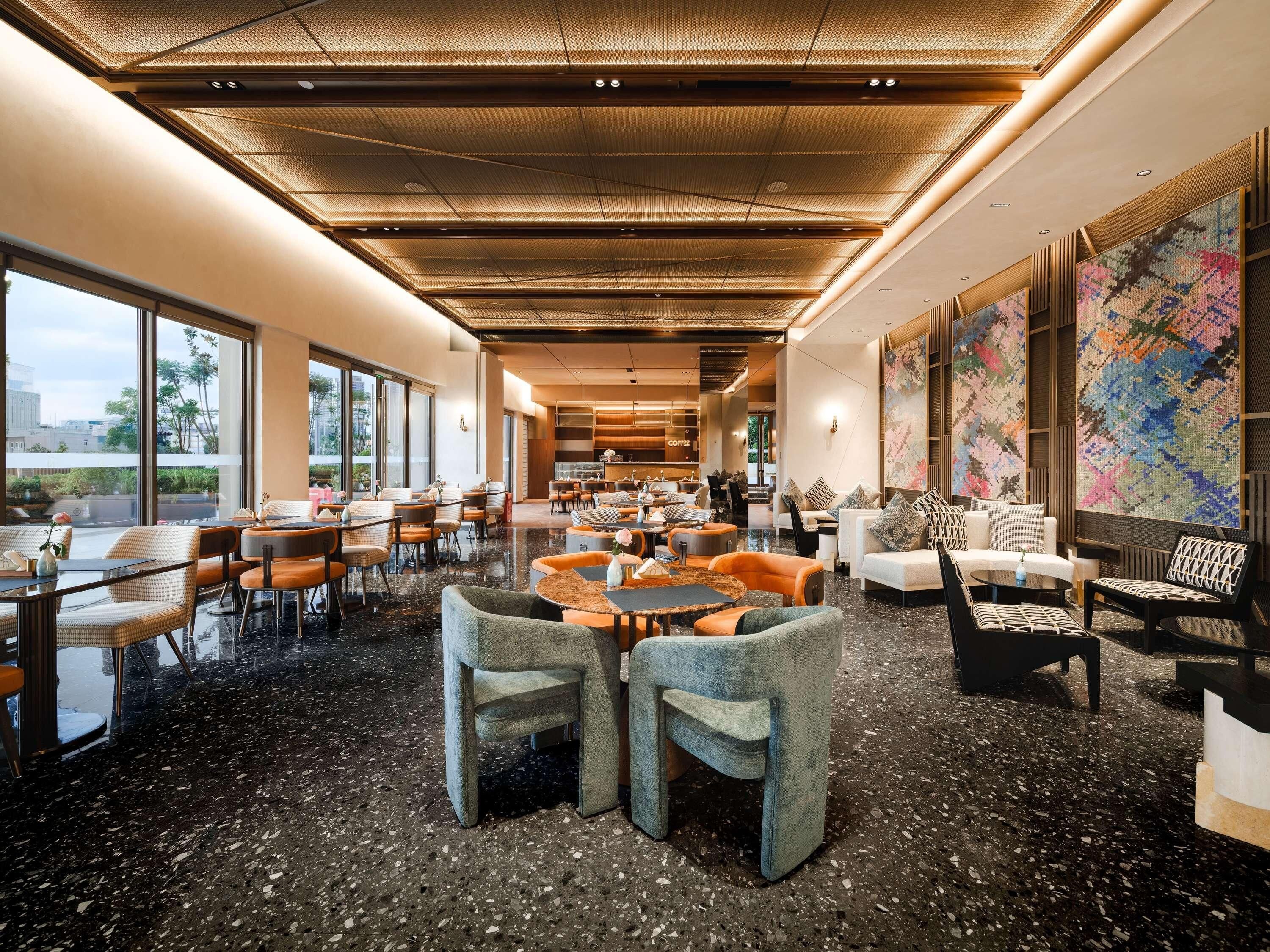 A spacious lobby with a high ceiling, large windows, and a coffee bar.