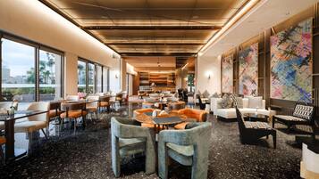 A spacious lobby with a high ceiling, large windows, and a coffee bar.