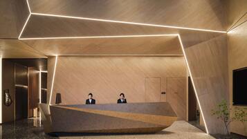 A modern reception area with a geometric reception desk, two staff members, and a minimalist design.