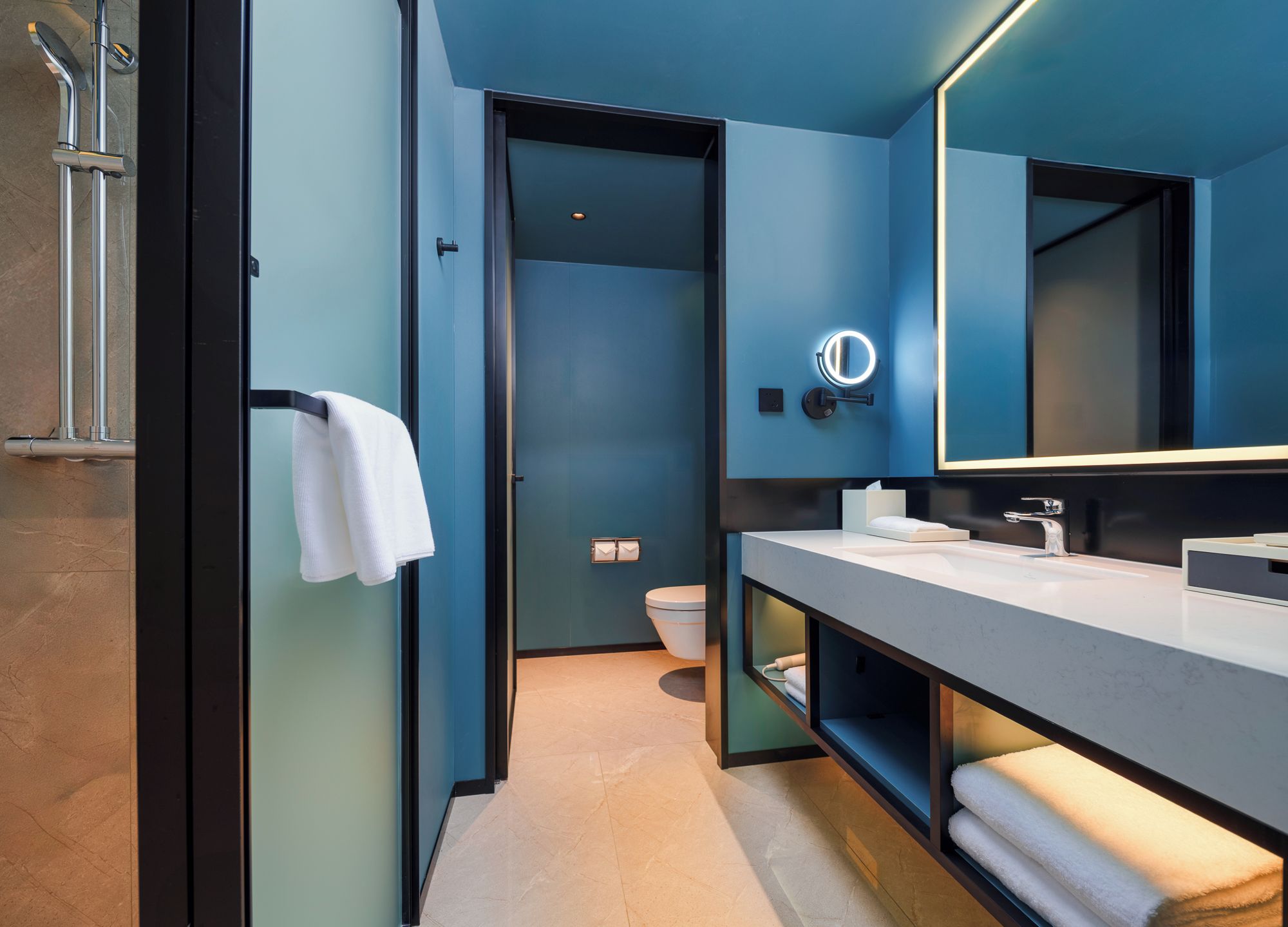 A modern bathroom with a large mirror, a towel rack, and a toilet.