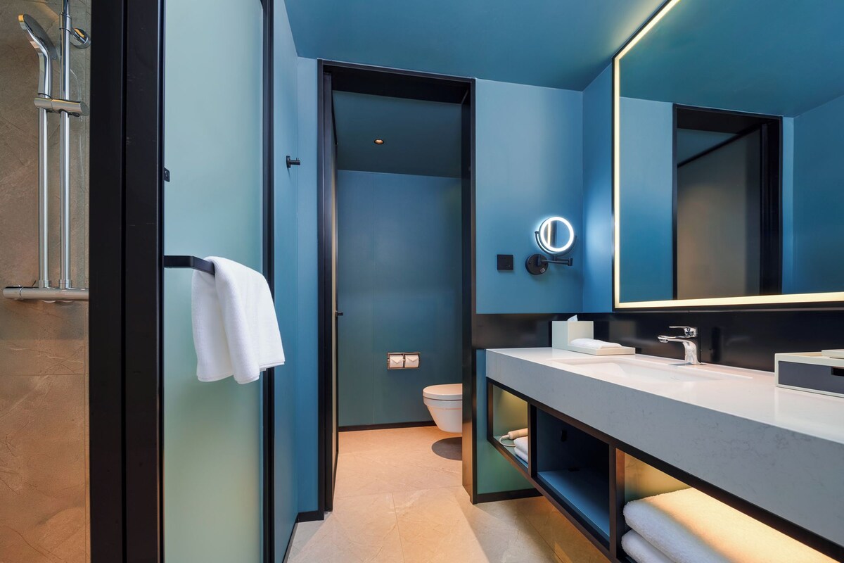 A modern bathroom with a large mirror, a towel rack, and a toilet.