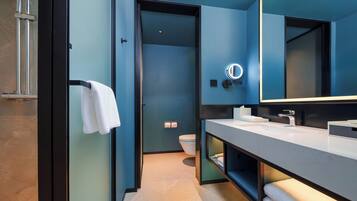 A modern bathroom with a large mirror, a towel rack, and a toilet.