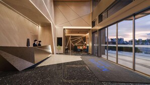 A modern hotel lobby with a reception desk, seating area, and large windows offering city views. - Novotel Kunming Yunjin (Kunming)