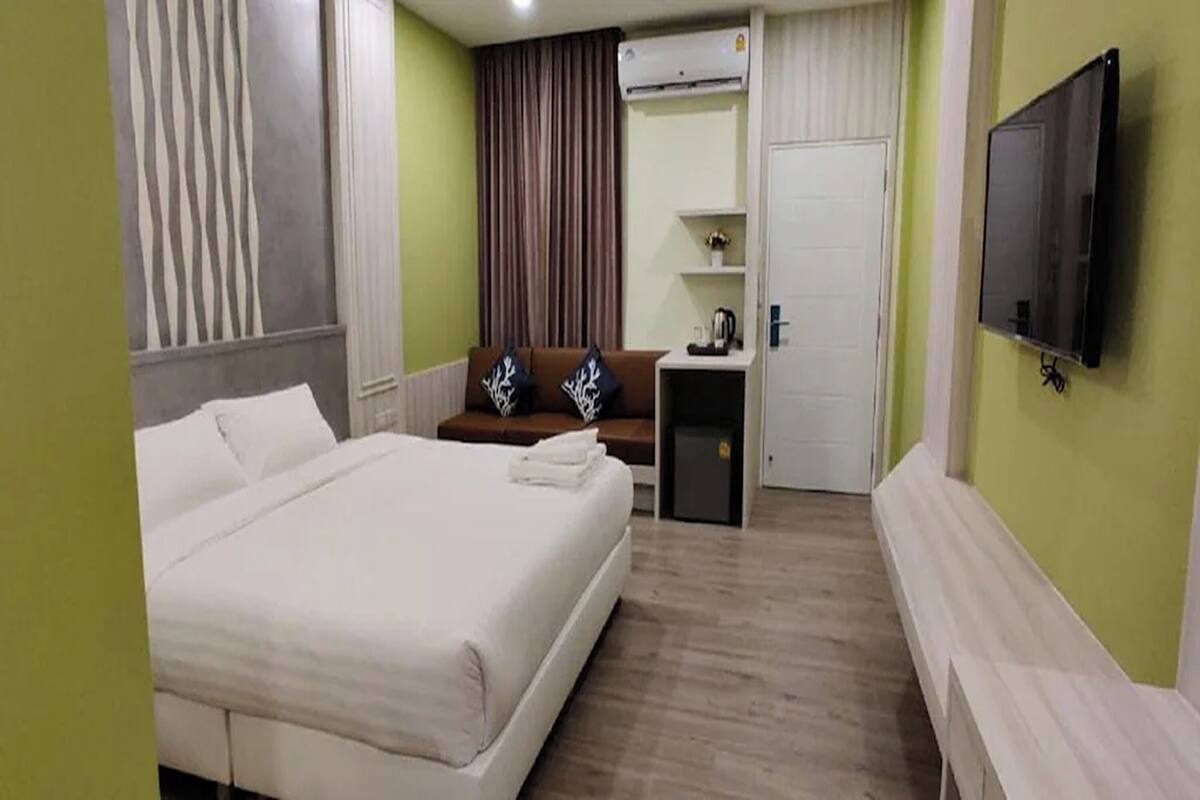 A hotel room with a bed, a desk, a TV, and a wardrobe.