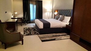A hotel room with a bed, desk, chair, and a view of the outdoors through a window. - Tulip Inn Majan Hotel (Salalah)