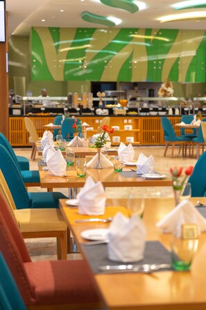 A restaurant with tables set for dining, chairs, and a buffet area in the background. - Tulip Inn Majan Hotel (Salalah)