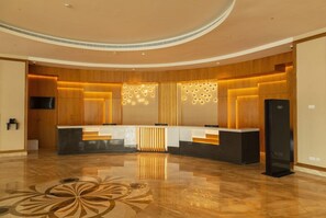 A modern reception area with a curved design, a central counter, and a polished floor. - Tulip Inn Majan Hotel (Salalah)