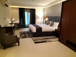 A hotel room with a bed, desk, chair, and a view of the outdoors through a window. - Tulip Inn Majan Hotel (Salalah)