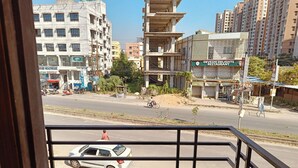 Uitzicht vanaf een balkon op een straat met gebouwen, een restaurant en een witte auto aan de kant geparkeerd.