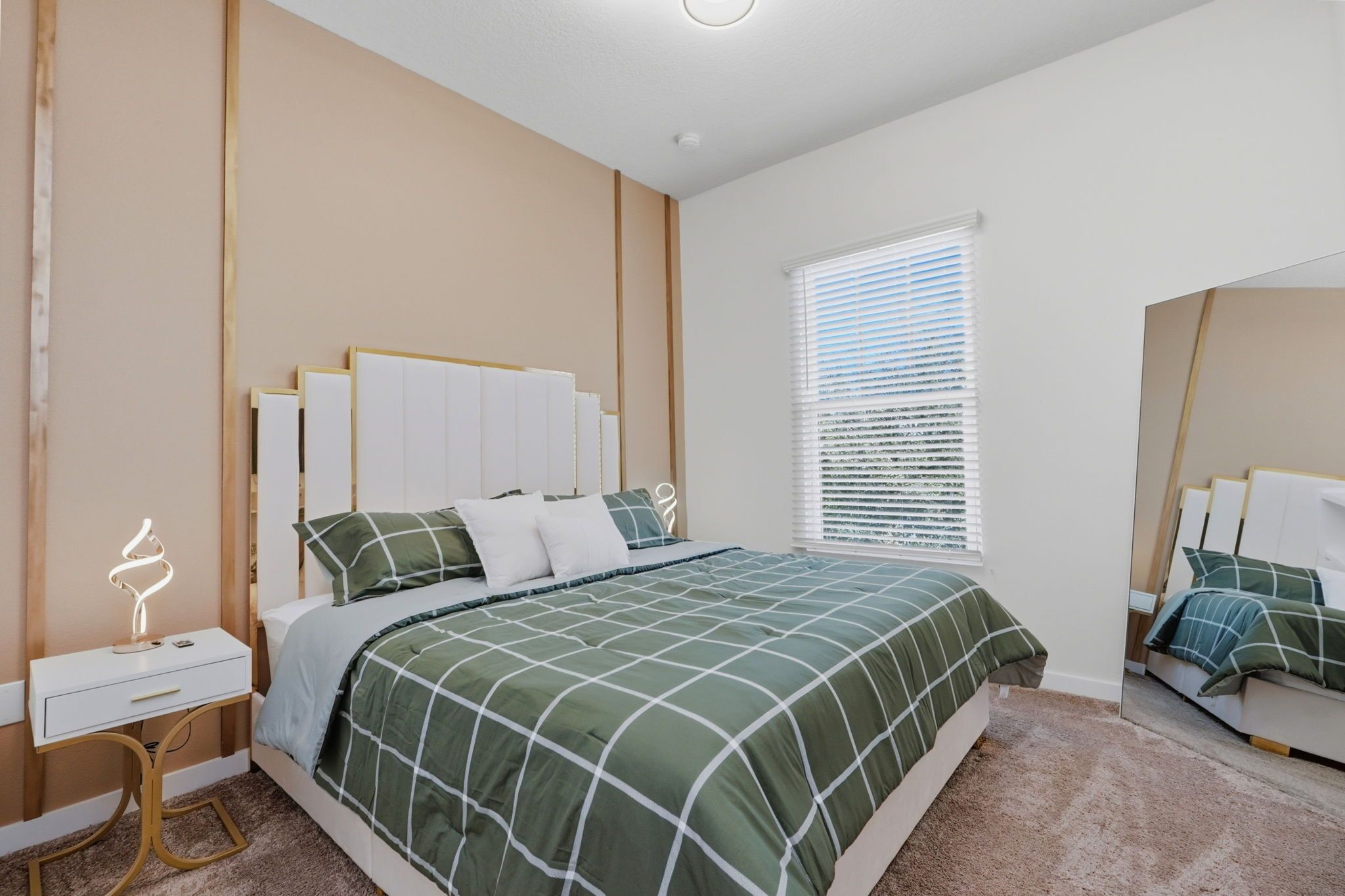 Quarto com cama, mesa de cabeceira e janela com persianas.