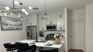 A modern kitchen with white cabinets, stainless steel appliances, and a central island with bar stools.
