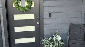 A black door with a wreath and a doormat.