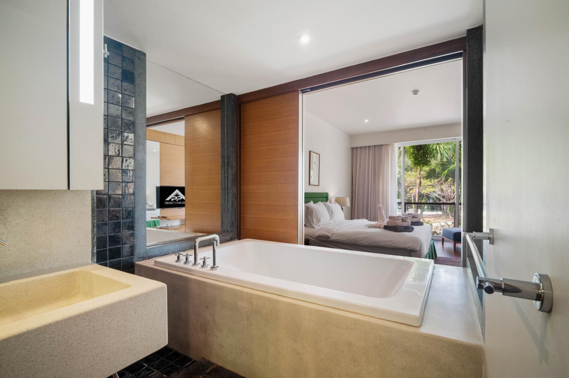 Un baño moderno con bañera, lavamanos y un espejo grande.