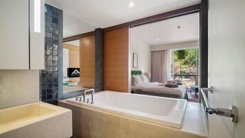 Un baño moderno con bañera, lavamanos y un espejo grande.