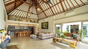 Un amplio espacio habitable con techo alto, vigas de madera y un gran ventanal.