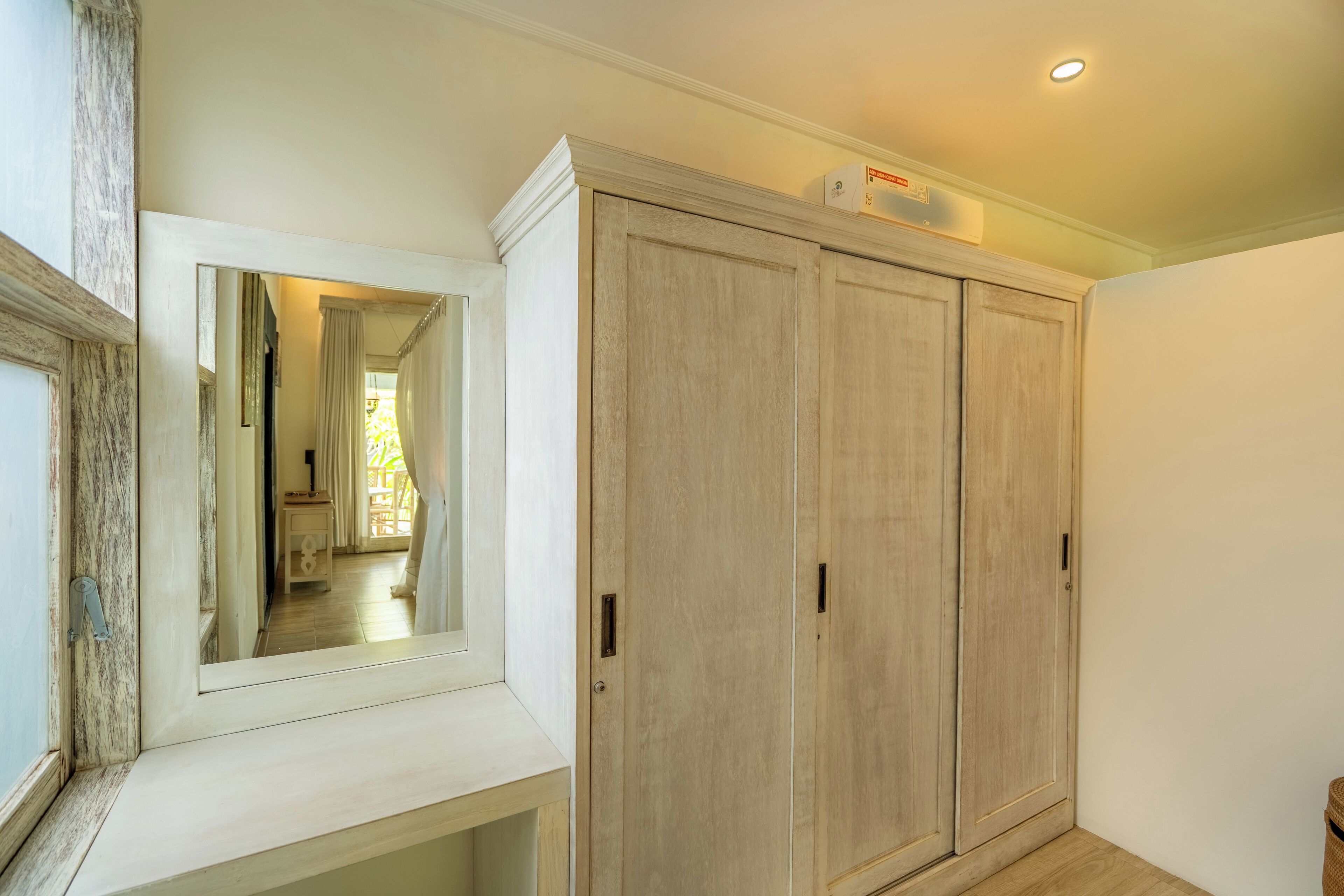 A hallway with a large wardrobe, a mirror, and a ceiling light.