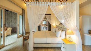 Un dormitorio amplio con una cama grande, una mesita de noche y un dosel con cortinas translúcidas.