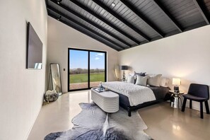 A modern bedroom with a large bed, a seating area, and a view of the outdoors. - 8 mins from Round Top Luxury Casita overlooking breathtaking views! (Burton)