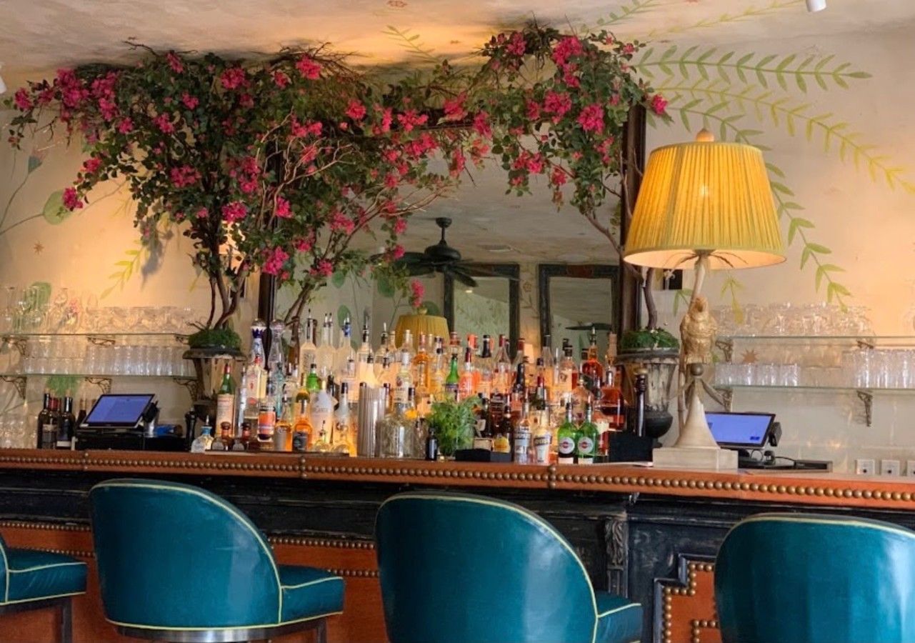 A bar area with a counter, bar stools, and a variety of bottles.
